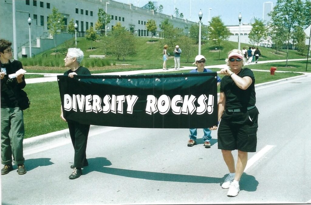 Two people holding a banner that says “diversity rocks!”.